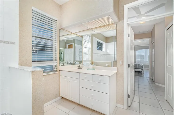 Ensuite bathroom with light tile patterned flooring and vanity