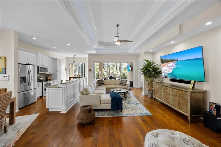 Living room featuring a tray ceiling, ceiling fan, dark hardwood / wood-style flooring, and ornamental molding