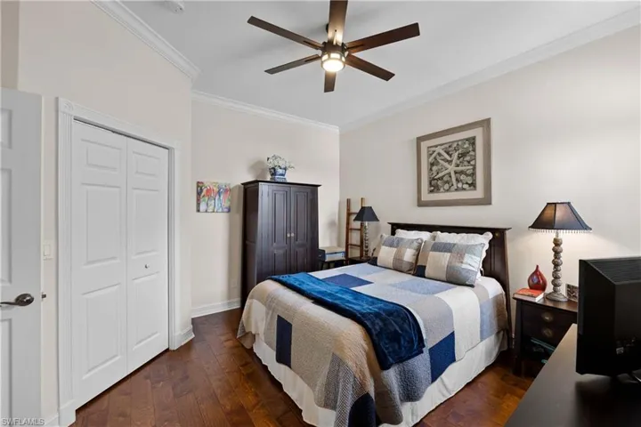 Bedroom with ceiling fan, dark hardwood / wood-style floors, ornamental molding, and a closet