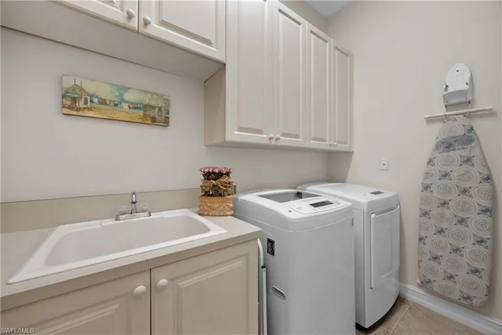 Washroom with cabinets, separate washer and dryer, light tile patterned flooring, and sink