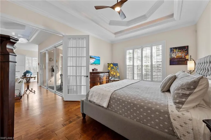 Bedroom featuring hardwood / wood-style floors, ceiling fan, crown molding, and french doors