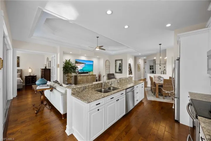 Kitchen with sink, a raised ceiling, pendant lighting, white cabinets, and appliances with stainless steel finishes