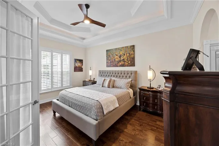 Bedroom with ceiling fan, dark hardwood / wood-style flooring, and ornamental molding