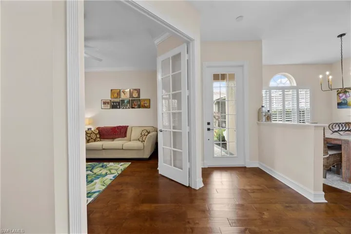 Doorway to outside featuring ceiling fan with notable chandelier, crown molding, and dark wood-type flooring