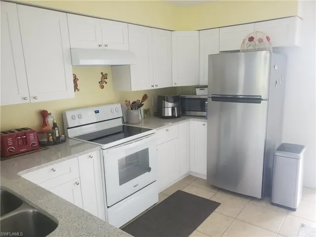 Kitchen with granite counters,  white   cabinets, and light tile floors