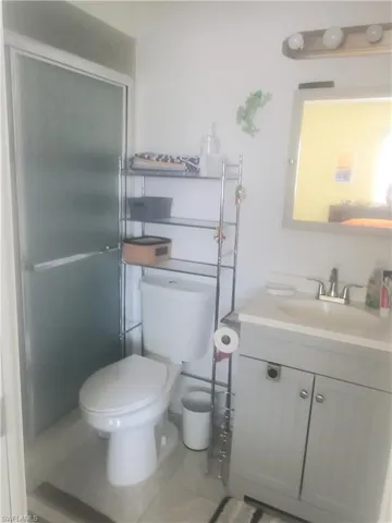 Bathroom with walk in shower, vanity, tile patterned flooring, and toilet