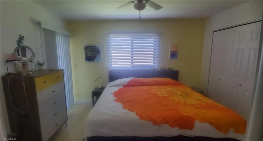 Tiled bedroom featuring ceiling fan and a closet