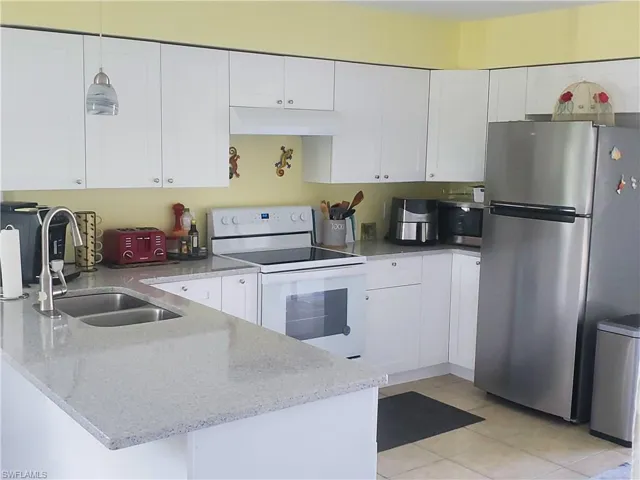 Kitchen featuring Whirlpool stainless steel fridge, white cabinets, Whirlpool electric stove, and granite countertops