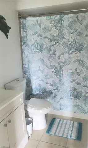 Bathroom featuring shower/bath combo, tile patterned floors, vanity, and toilet
