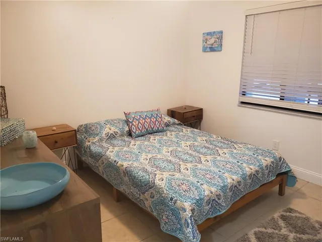 Bedroom with light tile floors and ceiling fan.