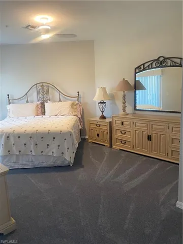 Bedroom with dark colored carpet and a ceiling fan