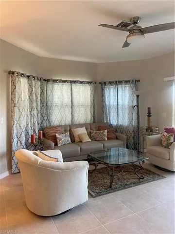 Living area featuring light tile patterned floors and ceiling fan