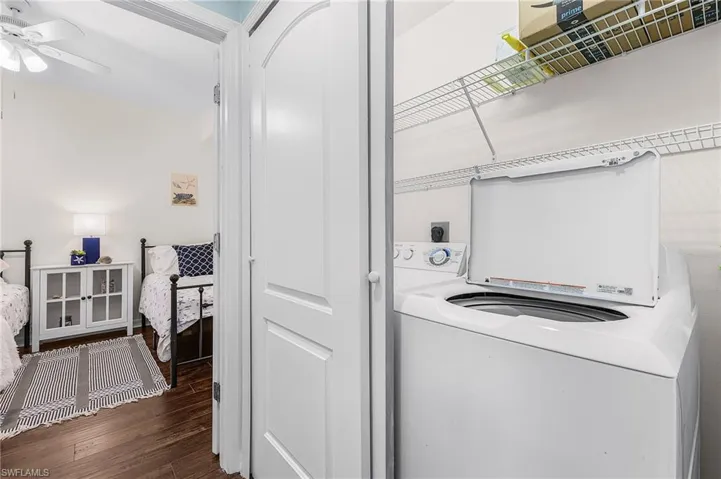 Laundry area with electric dryer hookup, dark wood finished floors, and a ceiling fan