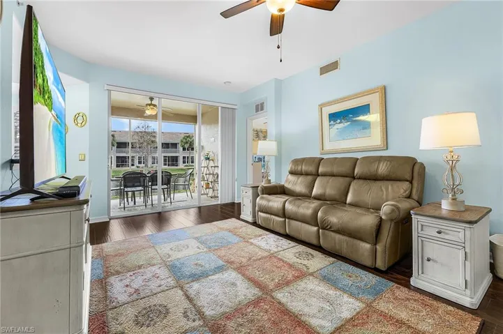 Living area featuring a ceiling fan and dark wood-style flooring