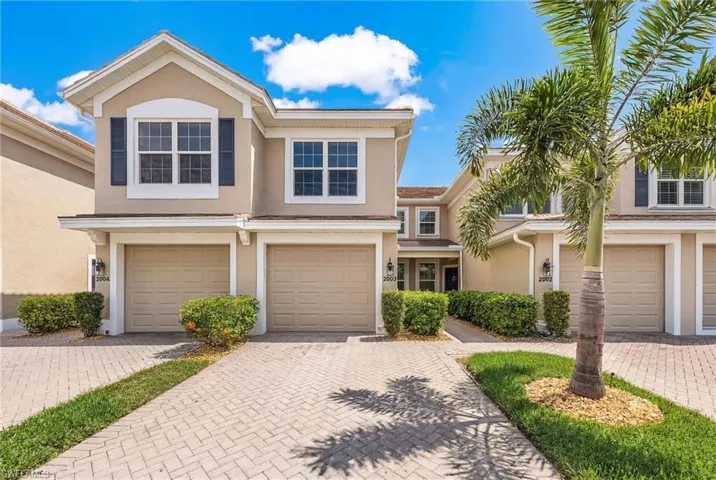 Traditional-style house with stucco siding, decorative driveway, and a garage
