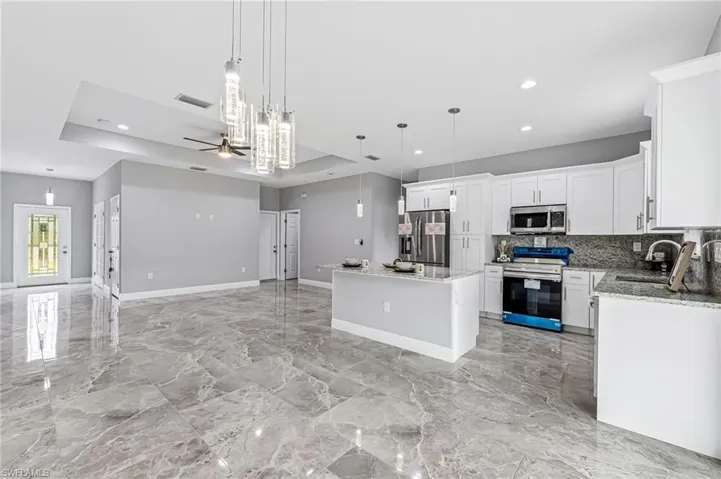 Kitchen featuring a center island, hanging light fixtures, ceiling fan, and stainless steel appliances