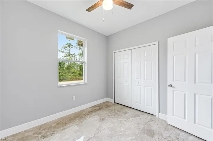 Unfurnished bedroom featuring ceiling fan, a closet, and light tile flooring