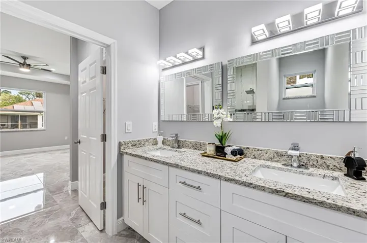 Bathroom featuring dual vanity, ceiling fan, and tile floors
