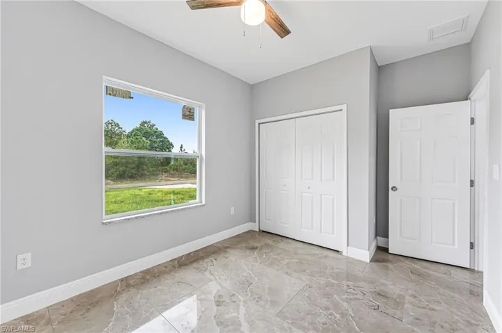 Unfurnished bedroom with ceiling fan, a closet, and light tile floors
