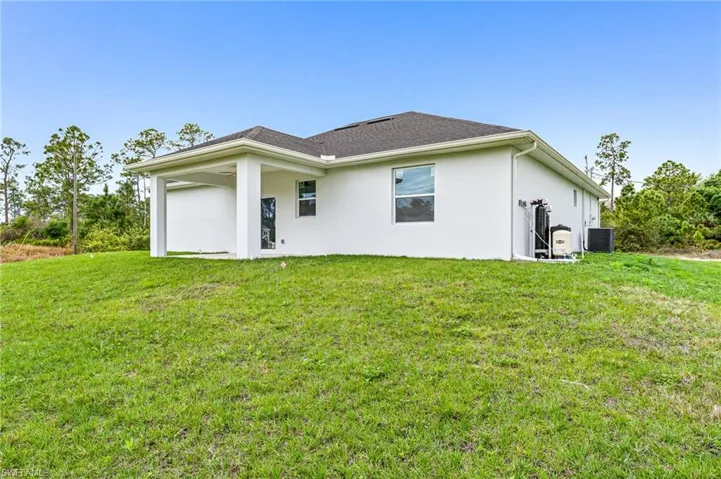 Back of house with central AC and a yard