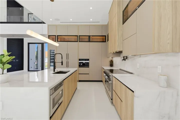 Gourmet kitchen fully equipped with luxury appliances including a Liebherr built-in dual-zone wine cooler, Viking flat range with double convection ovens, integrated dishwasher, custom built-in Liebherr side-by-side refrigerator/freezer, and Miele integrated coffee system.