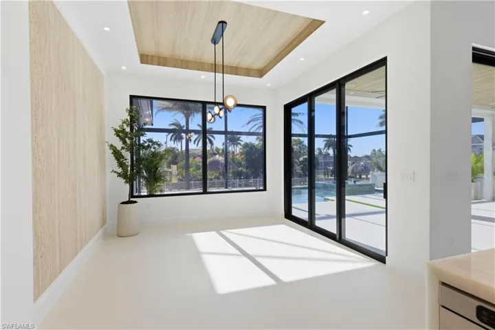 Formal dining room with 9-ft-tall TINTED LOW-E SLIDING DOORS leading to SCREENED LANAI & OVERSIZED WINDOWS to WATERFRONTAGE offer views of MALALUKA CANAL, POOL & SPA, PATIO & PRIVATE DOCK.
