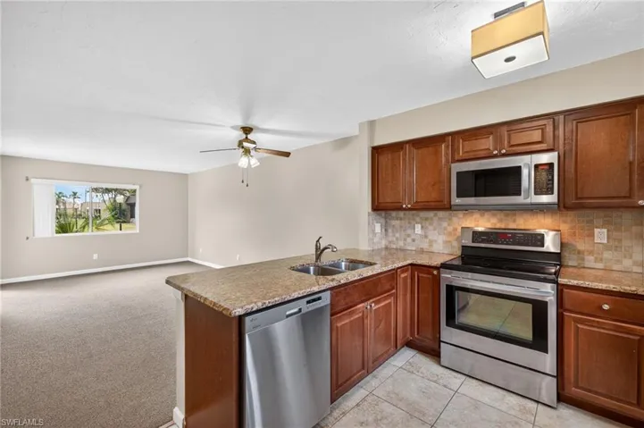 Kitchen with stainless steel appliances, ceiling fan, a peninsula, and wood finish cabinets
