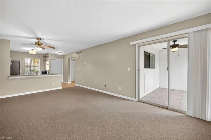 Unfurnished living room featuring ceiling fan and light carpet