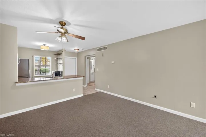 Unfurnished living room featuring ceiling fan and light colored carpet