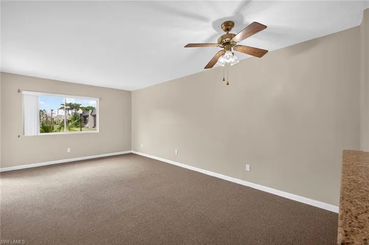 Carpeted empty room with baseboards and a ceiling fan