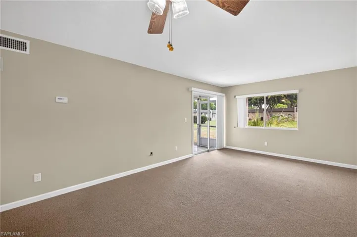 Carpeted spare room featuring baseboards and ceiling fan