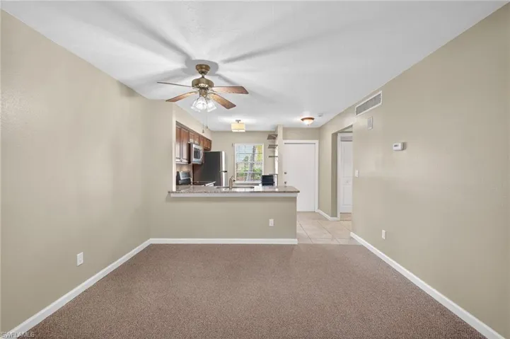 Unfurnished living room featuring a ceiling fan and light carpet