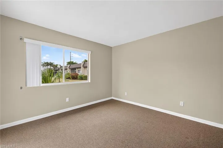 Carpeted spare room featuring baseboards