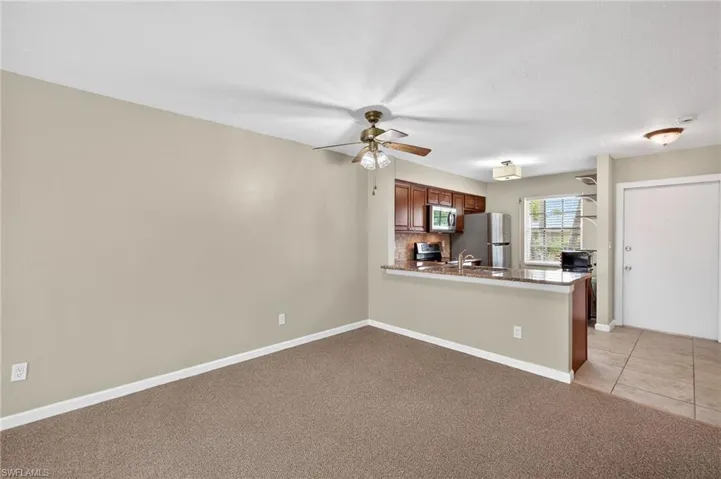Kitchen with light carpet, stainless steel appliances, ceiling fan, a peninsula, and backsplash