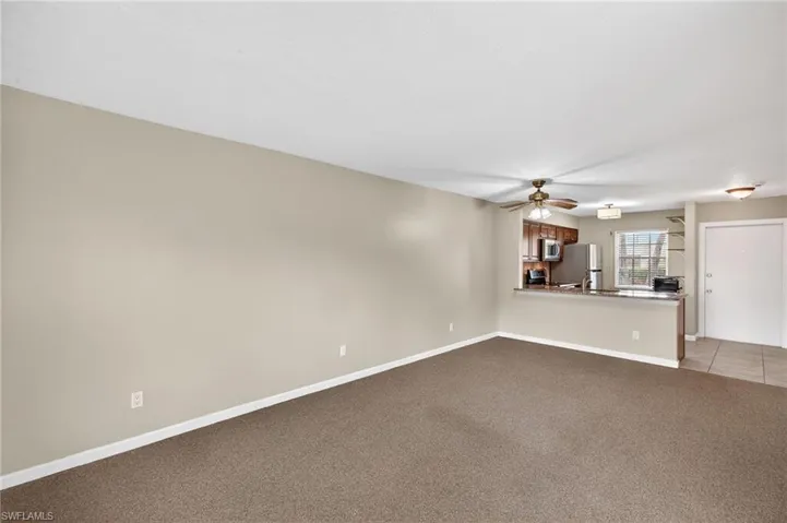 Unfurnished living room featuring a ceiling fan and light carpet