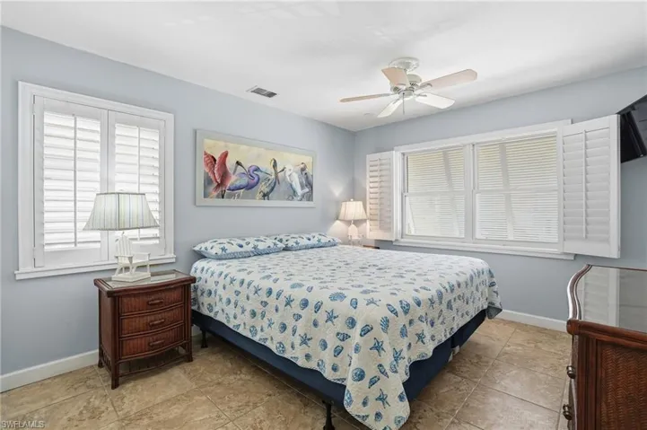 Spacious room featuring two windows with white plantation shutters, a ceiling fan, and tile flooring