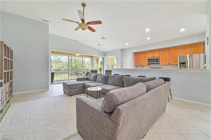 Living room featuring light tile patterned floors, lofted ceiling, ceiling fan, and recessed lighting