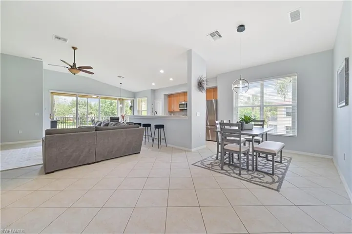 Dining room featuring vaulted ceiling, light tile patterned floors, plenty of natural light, a ceiling fan, and recessed lighting