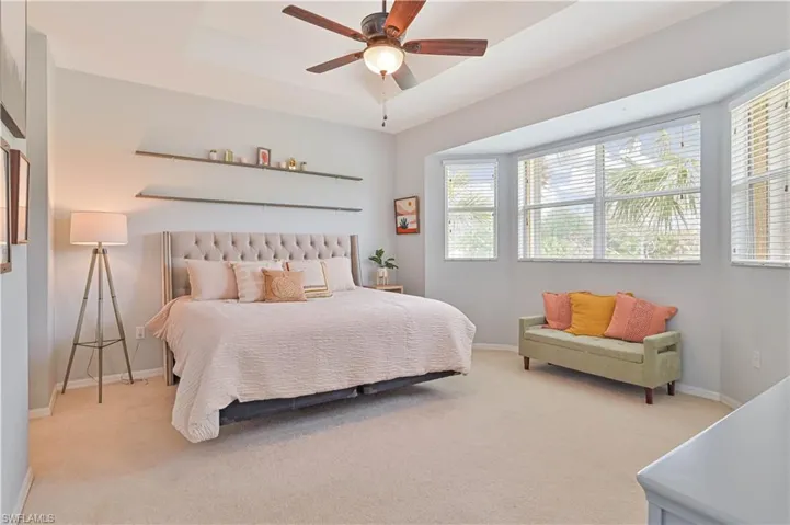 Bedroom featuring a tray ceiling, carpet floors, and ceiling fan