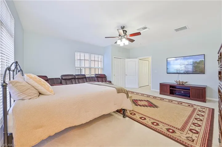 Bedroom with a closet, ceiling fan, and light colored carpet