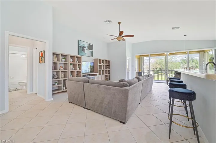 Living room featuring light tile patterned floors, vaulted ceiling, and a ceiling fan