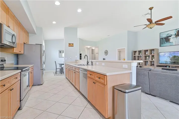 Kitchen featuring stainless steel appliances, open floor plan, a peninsula, light wood finish cabinetry, and recessed lighting