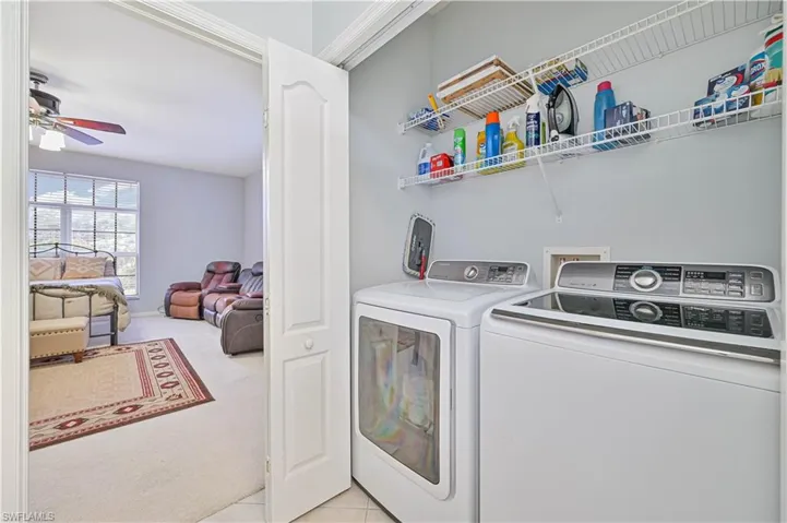 Laundry area with a ceiling fan, washing machine and clothes dryer, and light carpet