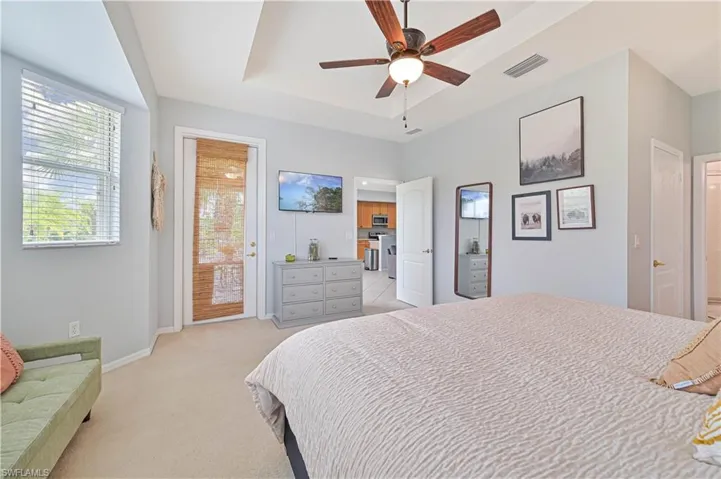 Bedroom featuring access to exterior, light carpet, a ceiling fan, and a tray ceiling
