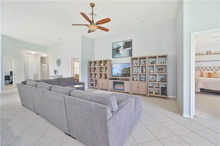 Living room featuring a ceiling fan, light tile patterned flooring, and a high ceiling