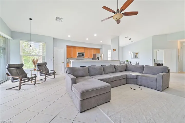 Living room featuring a ceiling fan, light tile patterned floors, recessed lighting, and lofted ceiling