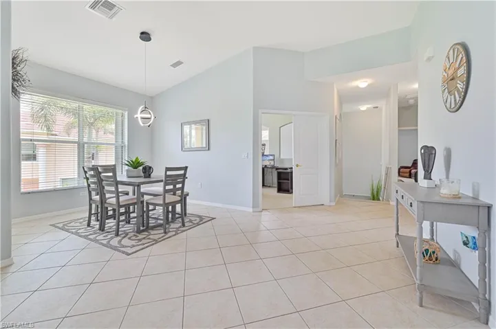 Dining space featuring light tile patterned floors and vaulted ceiling