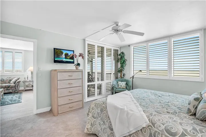 Carpeted bedroom with ceiling fan and multiple windows