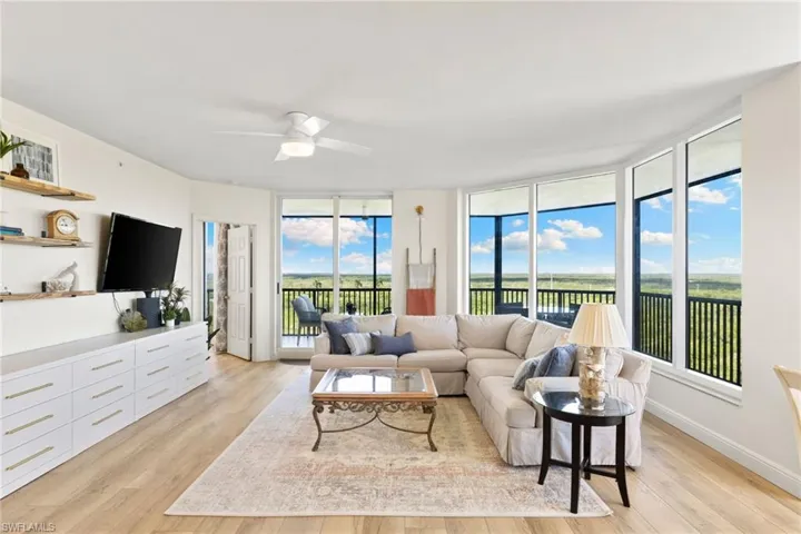 Living area featuring expansive windows, light wood-style flooring, and ceiling fan