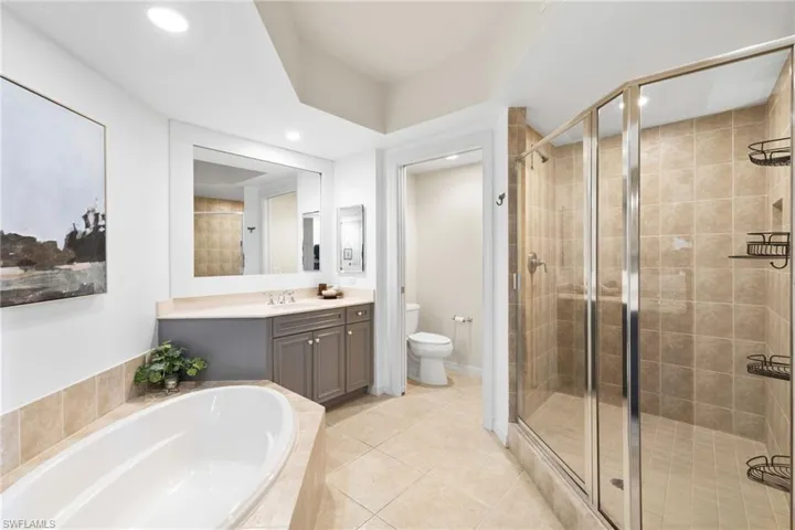 Bathroom featuring vanity, a garden tub, a stall shower, light tile patterned flooring, and recessed lighting